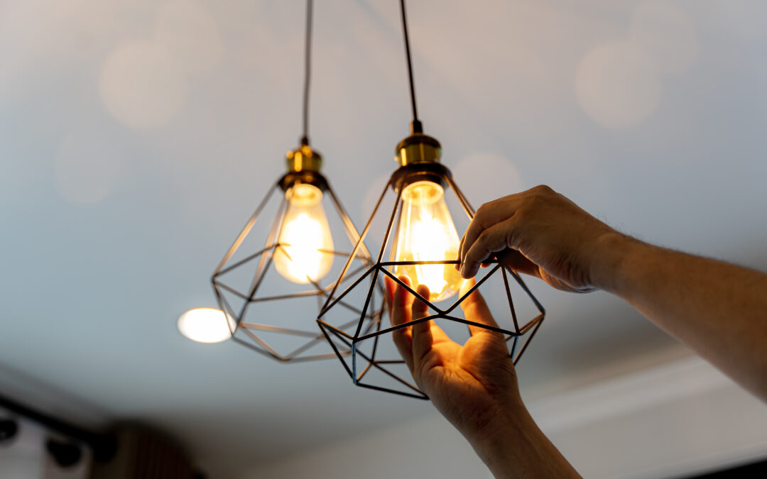 Decorative antique edison style filament light bulbs hanging. An electrician is installing spotlights on the ceiling